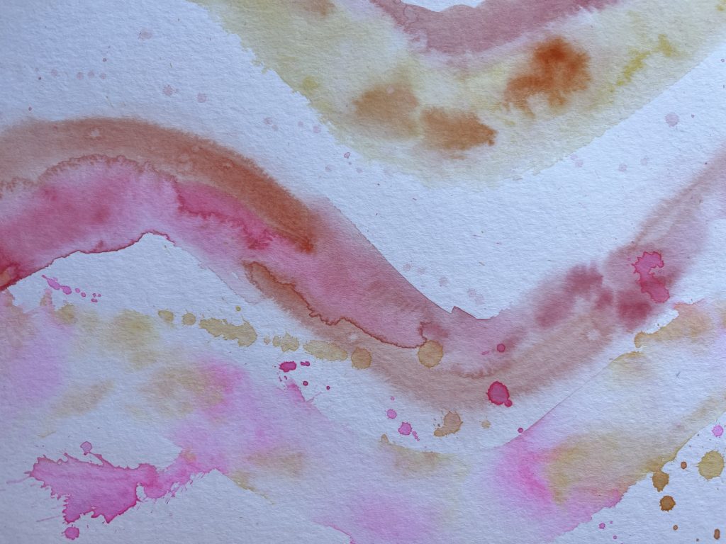watercolour paint in random patterns with pinks, oranges and yellows combining to make a wave